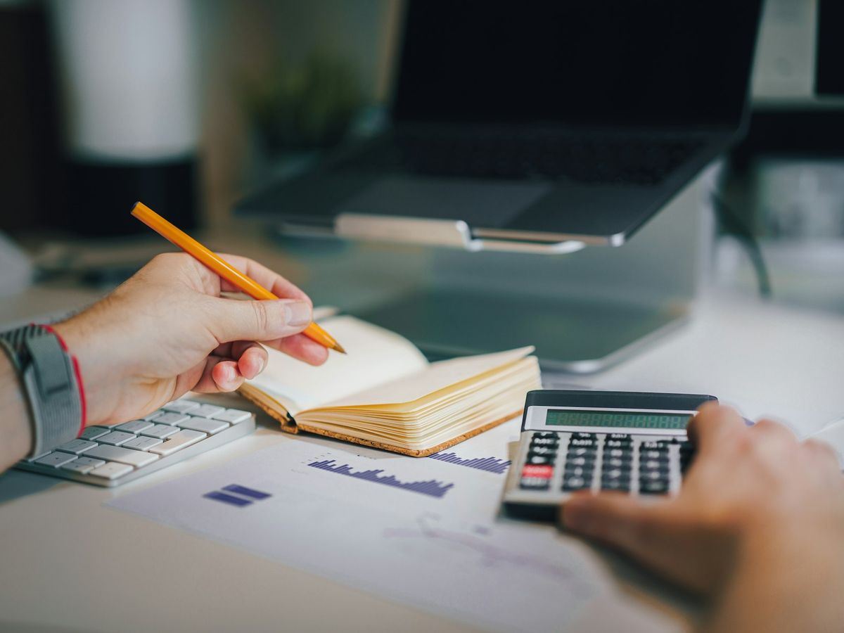 A desk with a calculator, a notebook and printed financial reports.